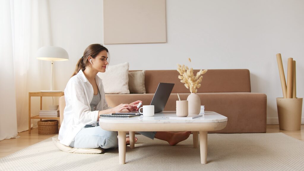 Woman sitting on floor using her laptop on a low coffee table